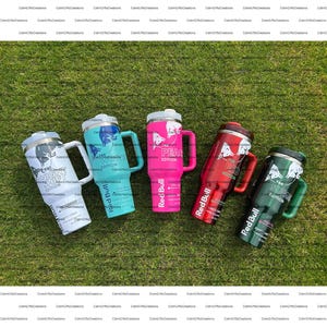 Pu&ograve; includere: Cinque bicchieri isolanti con manici sono esposti sull'erba. Ogni bicchiere ha un colore e un design diversi, inclusi i testi "NIGHT SHIFT EDITION", "WINTER EDITION", "PEACE EDITION", "RED EDITION" e "SUMMER EDITION". Il logo Red Bull &egrave; visibile.