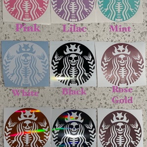 May include: Nine different coloured stickers featuring a skeleton with a crown and a mermaid tail, in the style of the Starbucks logo. The colours are pink, lilac, mint, white, black, rose gold, holographic orange, holographic grey, and holographic pink.