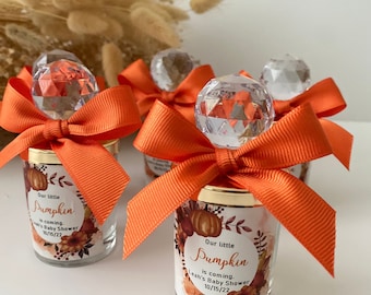May include: Four small glass jars with orange ribbon bows and crystal tops. Each jar has a label with a pumpkin design and the text "Our little Pumpkin is coming. Leah's Baby Shower 10/15/22".