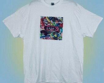 May include: White t-shirt with a colorful graphic print of a skateboard and other toys. The graphic includes the word "420" on the skateboard.