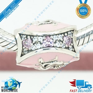 May include: A silver charm with a pink enamel heart design. The charm is decorated with clear and pink cubic zirconia stones. The charm is labeled "Purity 925 Sterling Silver".