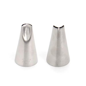May include: Two stainless steel piping tips with different shaped openings. One tip has a curved opening, and the other has a wide, flat opening. The number "227" is etched on the side of one tip. These are used for cake decorating.