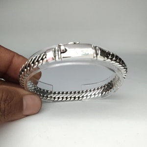 May include: A silver bracelet with a chain link design. The bracelet has a clasp closure.
