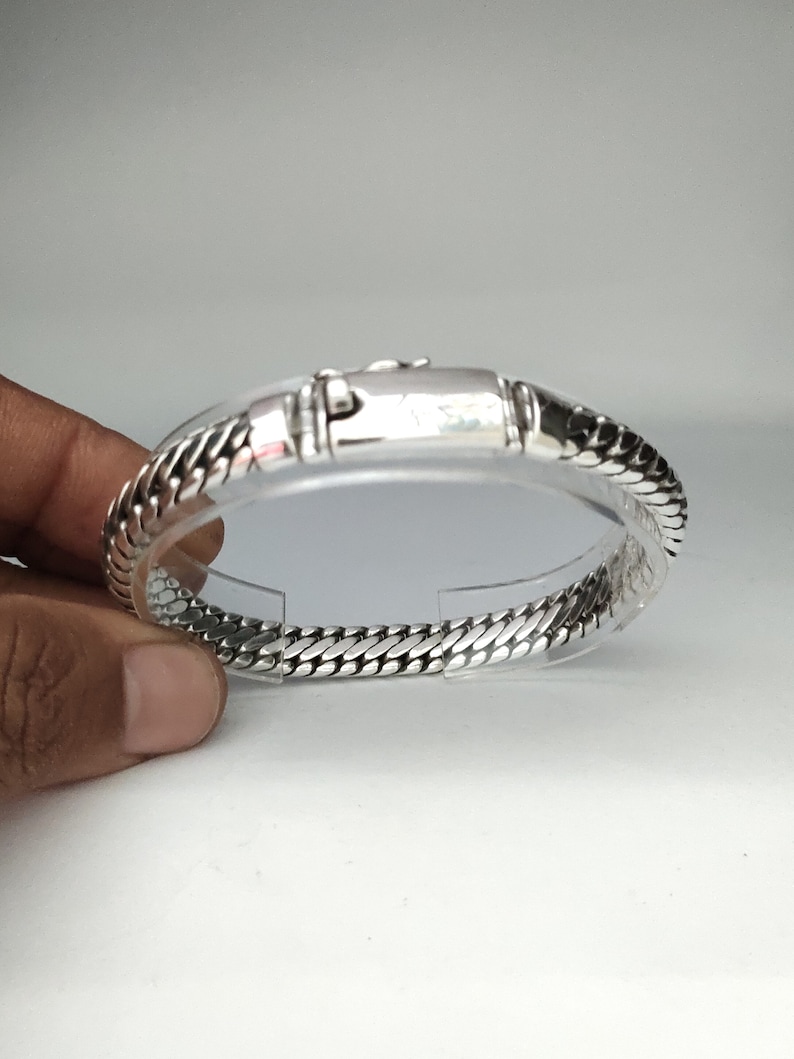 May include: A silver bracelet with a chain link design. The bracelet has a clasp closure.