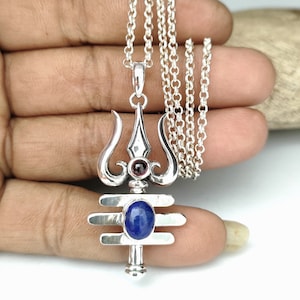 Peut inclure: Collier avec pendentif en argent représentant un trishul de Shiva avec une pierre de lapis-lazuli bleue et une pierre de grenat rouge.