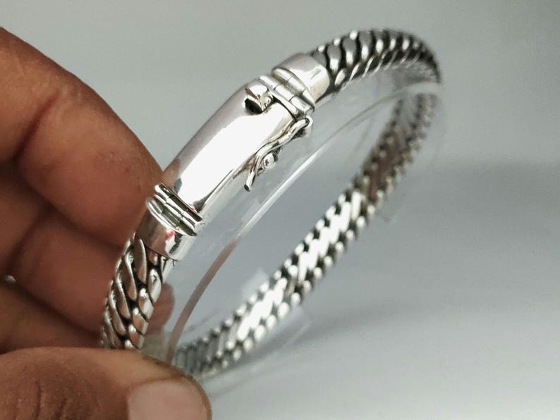 May include: A silver bracelet with a braided chain design and a clasp closure.