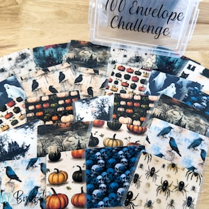 May include: A clear plastic container with the text "100 Envelope Challenge" on the lid. The container is filled with small cards featuring various Halloween-themed patterns, including pumpkins, ghosts, crows, skulls, and spiders.