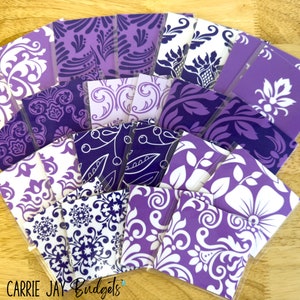May include: A collection of purple and white patterned fabric squares. The fabric squares are arranged in a fan shape and have a variety of floral and geometric designs.