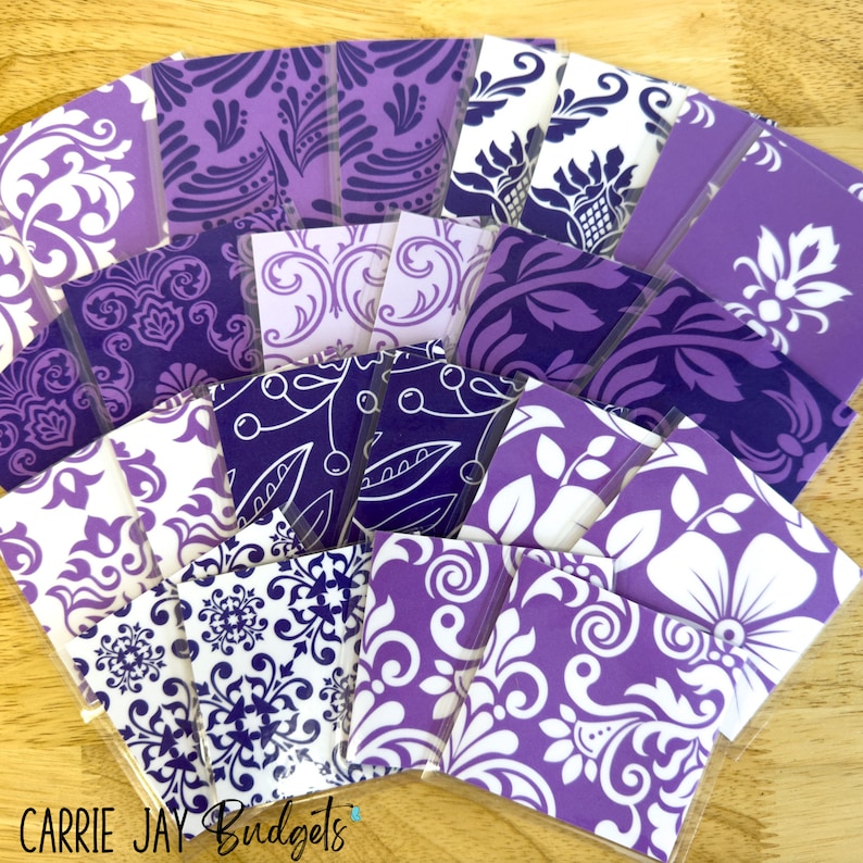 May include: A collection of purple and white patterned fabric squares. The fabric squares are arranged in a fan shape and have a variety of floral and geometric designs.