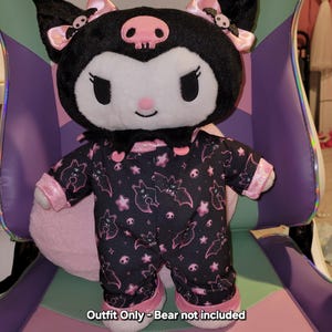 May include: Black and pink plush pyjama outfit with a bat and star pattern. Outfit Only - Bear not included.