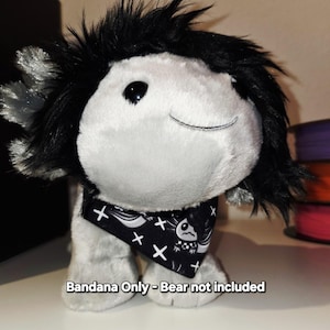 May include: Black and white bandana with a skull and crossbones design. The bandana has a black background with white skulls and crossbones. The text "Bandana Only - Bear not included" is visible at the bottom of the image.