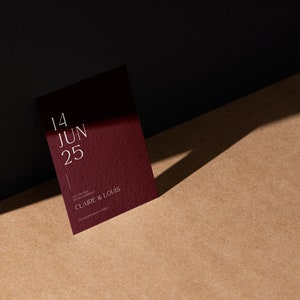 May include: A burgundy invitation card with white text that reads "14 JUN 25" and "CLAIRE & LOUIS".