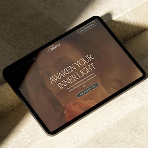May include: A black tablet displays a website with the word "Aurora" at the top. The text "Awaken Your Inner Light" is prominently featured, along with a call to action button. The background has a warm, inviting color palette.