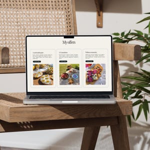 May include: A silver laptop displaying a webpage titled "My offers" sits on a light wood chair. The screen shows three sections with images and text. The chair has a woven back and is next to a plant.