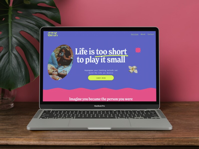 May include: A silver MacBook Pro laptop showing a website with the text "Life is too short to play it small." The website has a blue background with pink and yellow accents. The laptop is on a wooden surface.