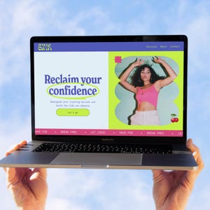 May include: A laptop screen showing a website with the words "Reclaim your confidence." The site features a woman in a pink top and white trousers. The laptop is held against a blue sky.