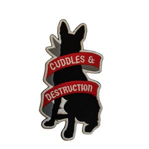 May include: Black and white embroidered patch of a dog with a red banner that says "Cuddles & Destruction".