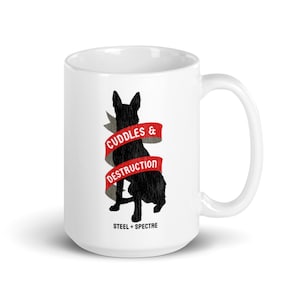 May include: White ceramic mug with a black silhouette of a dog and a red ribbon with the text "Cuddles & Destruction" and the text "Steel + Spectre" at the bottom.