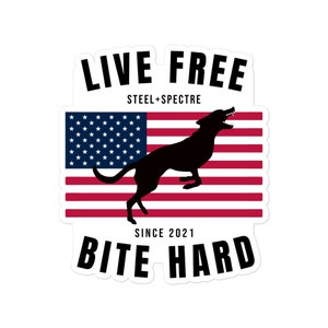 May include: A sticker featuring a black silhouette of a dog leaping in front of an American flag. The text "LIVE FREE" and "BITE HARD" are displayed in bold, black letters. The sticker also includes the text "STEEL+SPECTRE" and "SINCE 2021".