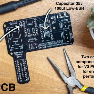 May include: A black V3 PCB with component labels, a screwdriver, and pliers. The PCB has text labels including "Diode 1N5819" and "Capacitor 35v 100uf Low-ESR". A succulent plant is in the background.