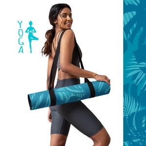 May include: A woman carrying a blue yoga mat with a tropical print. The mat has a black strap and is rolled up. The word "YOGA" is written in blue letters on the left side of the image.
