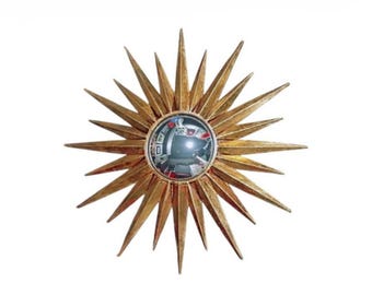 May include: A gold sunburst mirror featuring a central convex circular glass lens surrounded by numerous radiating pointed rays of varying lengths. The metallic finish has a textured appearance, creating a star-like shape with a reflective center.
