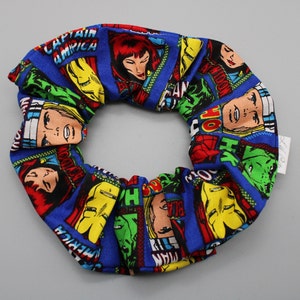 May include: A blue scrunchie with a comic book pattern featuring various Marvel superheroes, including Captain America, Hulk, Spider-Man, and Black Widow.