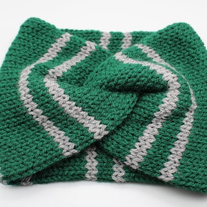 Puede incluir: Diadema de crochet a rayas verdes y grises. La diadema está retorcida y tiene una tela gruesa y texturizada.