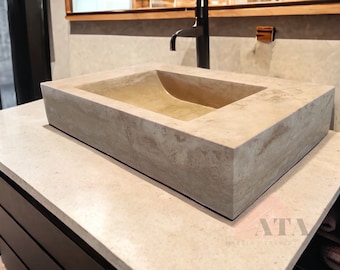 May include: A rectangular, off-white concrete vessel sink with a rounded, slightly curved interior. The sink is mounted on a countertop with a dark brown cabinet underneath.