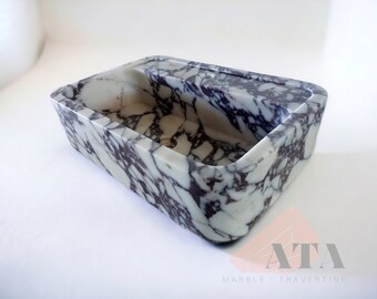 May include: A rectangular marble sink with a white and purple marbled pattern. The sink has a rounded edge and a drain hole.