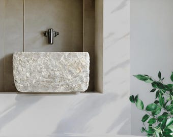 May include: A white stone sink with a rough, textured surface. The sink is mounted on a wall and has a single tap.