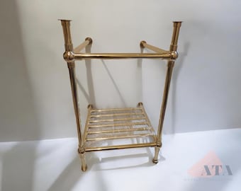 May include: Gold metal bathroom vanity stand with a shelf. The stand has two horizontal bars and a square shelf.
