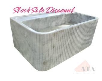 Puede incluir: Un lavabo rectangular de mármol blanco con un diseño acanalado. El lavabo está diseñado para ser montado en la pared.