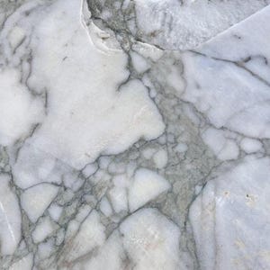 May include: Close-up of a marble surface with a natural pattern. The stone features a mix of white, gray, and subtle brown veining. The intricate veining creates a unique, organic design, suitable for home decor.