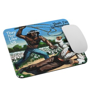May include: Rectangular mousepad with a painting depicting a Black person whipping a white person. The mousepad has the text "They Not Like US" and "Yeah I'm Whooping". A white computer mouse is next to the mousepad.