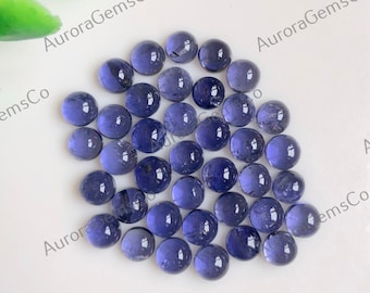 May include: A collection of round, smooth, purple gemstones. The gemstones are arranged in a loose pile on a white surface.