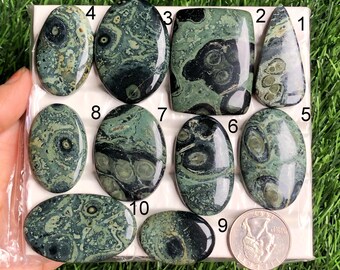 May include: Ten polished green and black ocean jasper cabochons, numbered 1 through 10, arranged on a white background. The cabochons are oval and teardrop shaped, with swirling patterns of green, black, and white.
