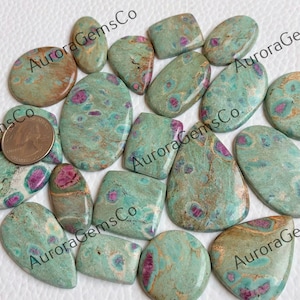 May include: A collection of 14 green and pink gemstone cabochons in a variety of shapes and sizes. The stones have a mottled appearance with brown, green, and pink hues.
