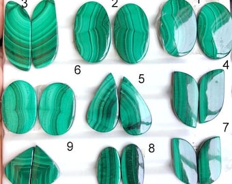 Puede incluir: Una colección de nueve pares de piedras preciosas de malaquita pulidas en varias formas, incluyendo ovaladas, en forma de lágrima y de hoja. Las piedras muestran un color verde vibrante con patrones de bandas distintivos.