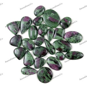 Puede incluir: Una colección de 20 piedras preciosas de zoisita verde y rosa, también conocidas como rubí en zoisita, en varias formas y tamaños. Las piedras son lisas y pulidas, con una mezcla de colores verde, rosa y negro.