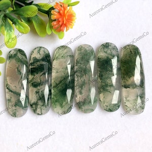 Può includere: Sei cabochon ovali in agata verde muschio con un aspetto traslucido e nuvoloso. Le pietre hanno un aspetto naturale e organico con motivi verdi e bianchi.