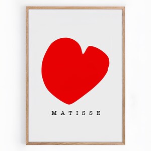 以下が含まれることがあります： 赤いハートの形と黒い文字で「MATISSE」と書かれた額装されたプリント