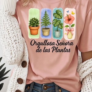 Op de afbeelding: Roze T-shirt met een aquarelontwerp van potplanten: een vetplant, een den, een monstera en een hibiscusbloem. De tekst "Orgullosa Señora de las Plantas" staat eronder gedrukt.