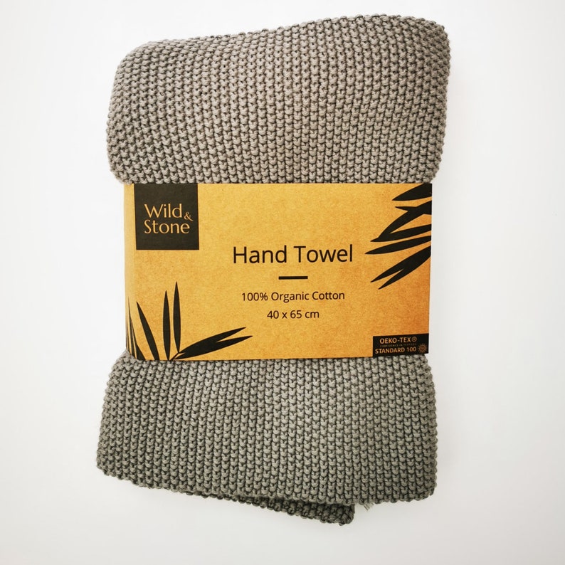 K&ouml;nnte beinhalten: Ein graues Handtuch aus 100% Bio-Baumwolle. Das Handtuch ist 40 cm x 65 cm gro&szlig; und hat ein braunes Etikett mit der Aufschrift "Wild & Stone Hand Towel 100% Organic Cotton 40 x 65 cm Oeko-Tex Standard 100".