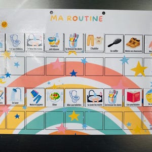 Może przedstawiać: Prostokątna magnetyczna tablica obowiązk&oacute;w z napisem MA ROUTINE, tęczowym tłem i kolorowymi gwiazdkami. Zawiera dwa rzędy ilustrowanych ikon zadań na poranek i wiecz&oacute;r oraz puste pola poniżej każdego rzędu do śledzenia codziennych postęp&oacute;w.
