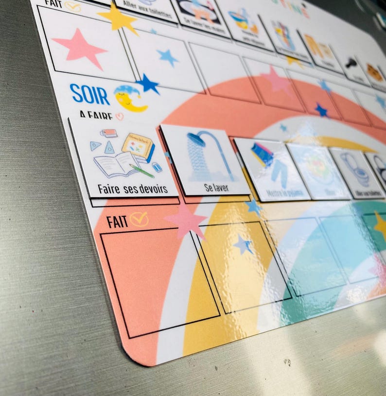 Może przedstawiać: Magnetyczna tablica obowiązk&oacute;w z motywem tęczy, gwiazd i księżyca. Tablica zawiera sekcje oznaczone jako SOIR A FAIRE i FAIT, z piktogramami zadań, takimi jak Faire ses devoirs, Se laver oraz Mettre le pyjama.