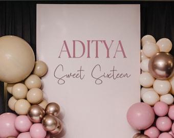 May include: A pink and beige balloon arch with the text "ADITYA Sweet Sixteen" on a white backdrop. The balloons are arranged in a cascading pattern, with the larger balloons at the top and the smaller balloons at the bottom.