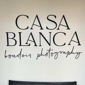May include: Black and white text on a white wall reads "Casa Blanca boudoir photography".