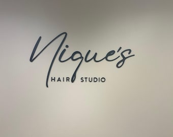 May include: A black sign with the text "Nique's Hair Studio" in a cursive font.