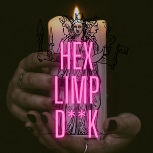 Puede incluir: Una vela blanca con una ilustración en blanco y negro de una mujer con tres cabezas sosteniendo una llave. El texto "HEX LIMP D**K" está escrito en letras rosas en la vela.